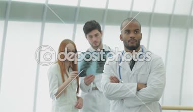 İki meslektaşının arka planında elinde x-ray olan genç bir doktorun portresi