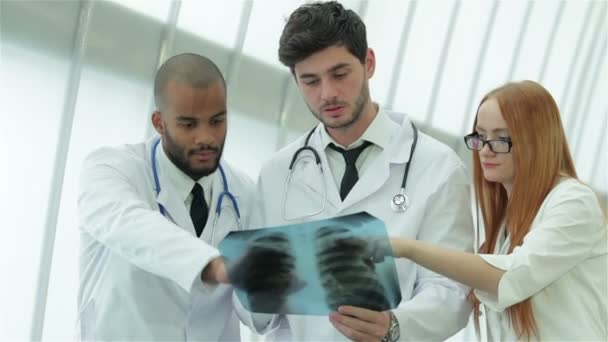 Tres médicos confiados examinando radiografía de los pulmones en el hospital — Vídeo de stock