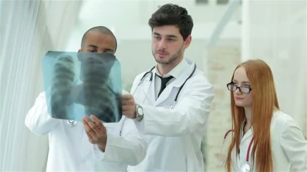 Tres médicos confiados examinando radiografía de los pulmones — Vídeo de stock