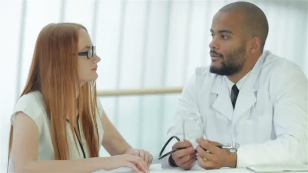 病院のテーブルに座りながら患者と話す医師 — ストック動画