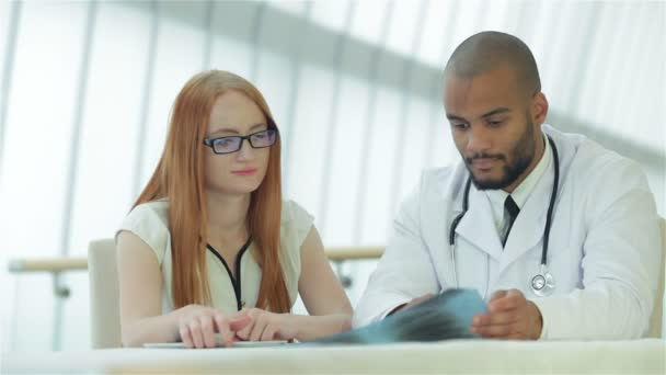 Ernstige arts praten met de patiënt en houdt borstkas X-Ray in de handen — Stockvideo