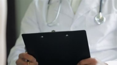 Bir doktor bir kağıt tutucu tutar ve yazıyor