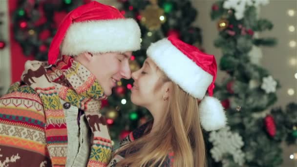 Pareja cariñosa vestida con suéter y bufanda en la habitación decorada de Navidad — Vídeo de stock