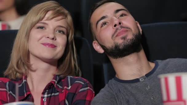 Young couple sitting in multiplex movie theater — Stockvideo