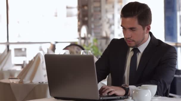 Άνθρωπος που χρησιμοποιεί φορητό υπολογιστή το μεσημέρι σε ένα καφέ — Αρχείο Βίντεο