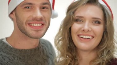 Santa şapkalı çift gülümseyerek ve gülüyor