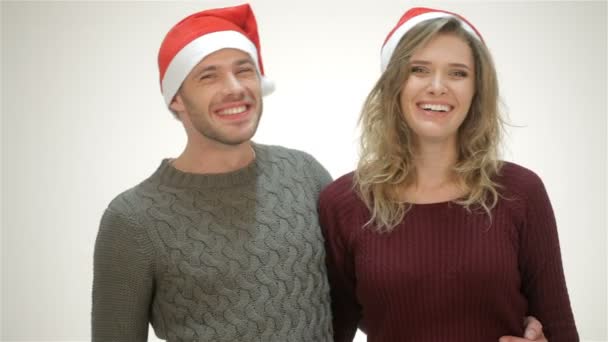 サンタ帽子の幸せなカップルは抱擁の中に立っている間に笑う — ストック動画