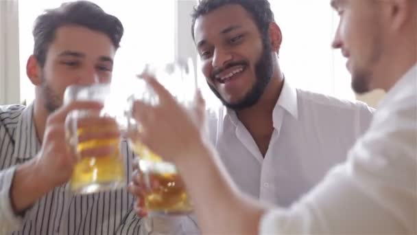 Felices amigos tintineando con tazas de cerveza en el pub — Vídeos de Stock