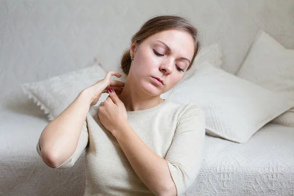 Mujer joven en casa tocándose el cuello en un estado de ánimo relajado — Foto de Stock