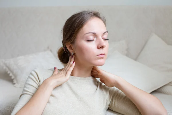 Mujer joven en casa tocándose el cuello en un estado de ánimo relajado — Foto de Stock