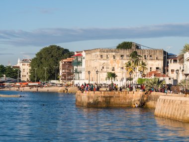 Taş şehirde sahil üzerinde yürüyen insanlar