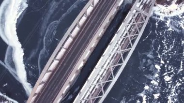 Bir köprü ve donmuş bir nehir üzerinde yumuşak bir uçuş, arabalar yol boyunca geçiyor, kış mevsimi, soğuk tonlar, yumuşak bir yükseliş ile bir bükülme
