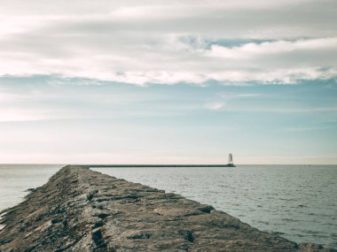 Limandaki büyük taşlardan yapılmış bir gölün inşaatı, deniz fenerinin sonunda, gökyüzü hafif bulutlu, mavi
