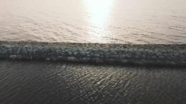 İHA 'nın gölün üzerinde pürüzsüz bir şekilde uçması. Ortasında taş bir patika var. Şafak vakti.