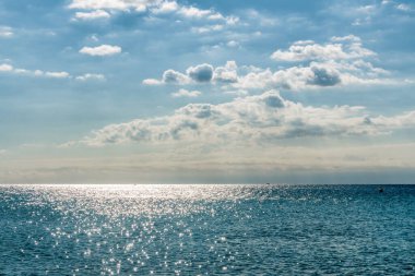 Mavi gökyüzü, güneş ve bulutlarla deniz manzarası