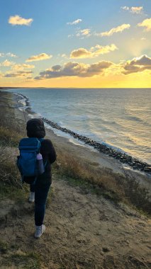 Gizli Ada 'da Baltık Denizi' nde gün batımını izleyen bir kadın.