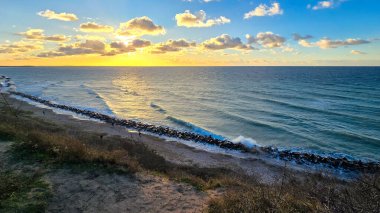 Gün batımında Hiddensee Adası 'nda sahilde yürüyen bir kadın.