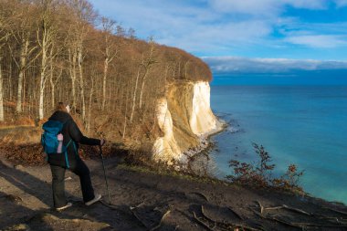Ruegen Adası 'ndaki Jasmund Ulusal Parkı' ndaki tebeşir kayalıklarından Baltık Denizi 'ne bakan sırt çantalı kadın.