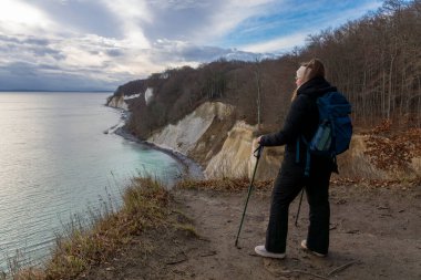 Ruegen Adası 'ndaki Jasmund Ulusal Parkı' ndaki tebeşir kayalıklarından Baltık Denizi 'ne bakan sırt çantalı kadın.