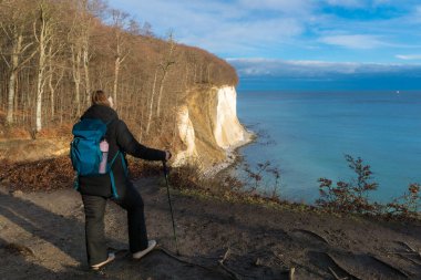Ruegen Adası 'ndaki Jasmund Ulusal Parkı' ndaki tebeşir kayalıklarından Baltık Denizi 'ne bakan sırt çantalı kadın.