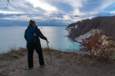 Ruegen Adası 'ndaki Jasmund Ulusal Parkı' ndaki tebeşir kayalıklarından Baltık Denizi 'ne bakan sırt çantalı kadın.