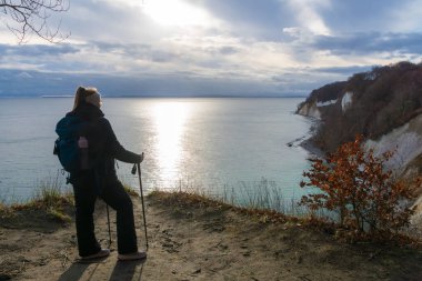 Ruegen Adası 'ndaki Jasmund Ulusal Parkı' ndaki tebeşir kayalıklarından Baltık Denizi 'ne bakan sırt çantalı kadın.