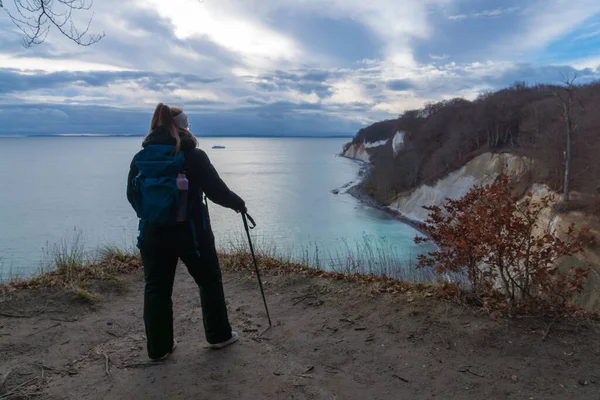Ruegen Adası 'ndaki Jasmund Ulusal Parkı' ndaki tebeşir kayalıklarından Baltık Denizi 'ne bakan sırt çantalı kadın.