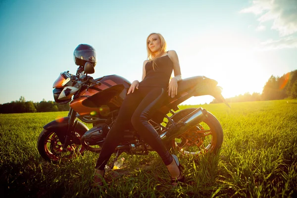 Молода красива блондинка на відкритому повітрі, позує з червоним мотоциклом. небо на фоні . — стокове фото