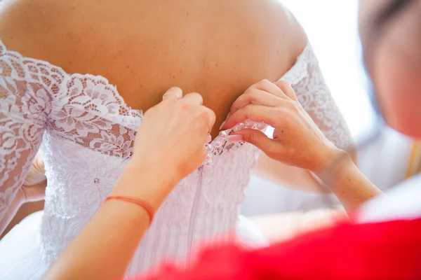 Noiva colocando em seu vestido de casamento branco — Fotografia de Stock