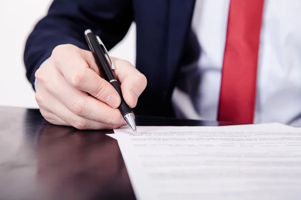 Un homme d'affaires signant un contrat. Une main tenant un stylo plume et sur le point de signer une lettre. Style et petite quantité de grain appliquée . — Photo