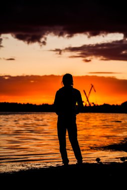 Güneş doğarken şehir manzaralı gökdelenin tepesinde duran kadın