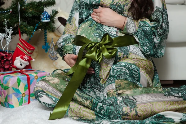 Femme enceinte est assis près de l'arbre de Noël à la maison — Photo