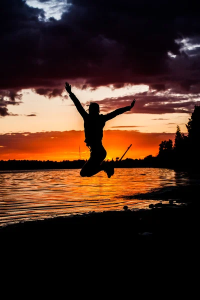Concetto di felicità e libertà. Silhouette uomo felice saltando su uno sfondo tramonto — Foto Stock