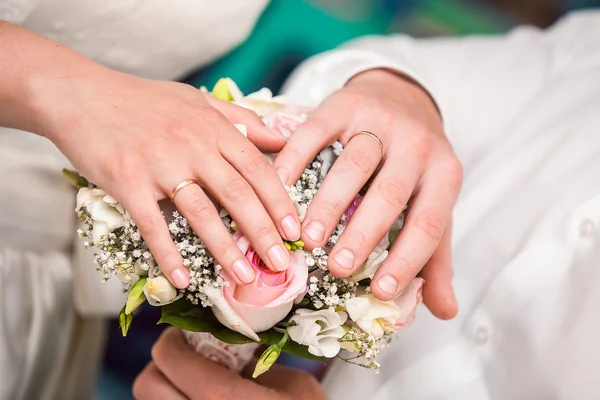 Händerna på brudgummen och bruden med vigselringar och en bröllop bukett — Stockfoto