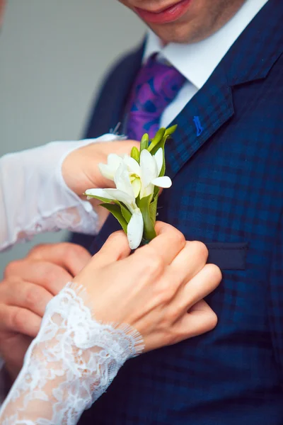 Aufhängen einer Braut, die boutonniere an der Jacke des Bräutigams anpasst — Stockfoto