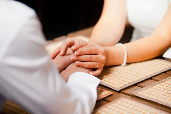 Nahaufnahme eines Mannes und einer Frau, die sich an einem Holztisch an den Händen halten — Stockfoto