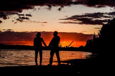 Gün batımı kırmızı güneş, hızlı tempo severler. Onun kollarında bir adam tutan kadın. Romantik akşam. Aşık Çift.