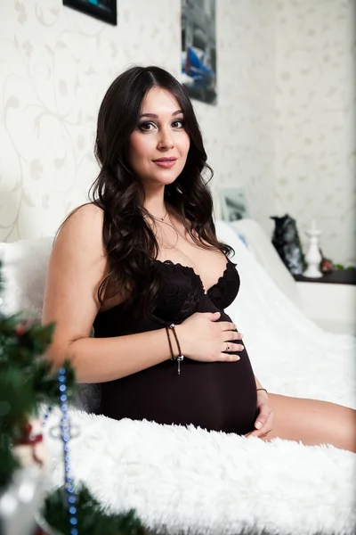 Underbar gravid kvinna poserar när hon ligger på en säng hemma — Stockfoto