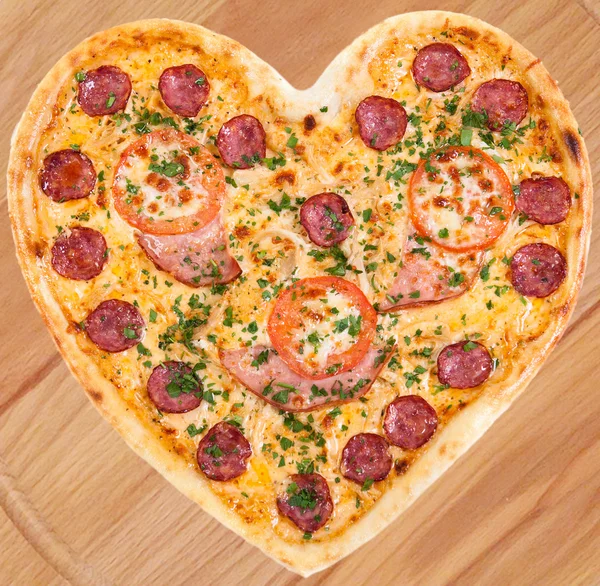 Et pizza jambon, salam, domates ve peynirle Sevgililer günü için kalp şeklinde taze İtalyan otlar ile tepesinde
