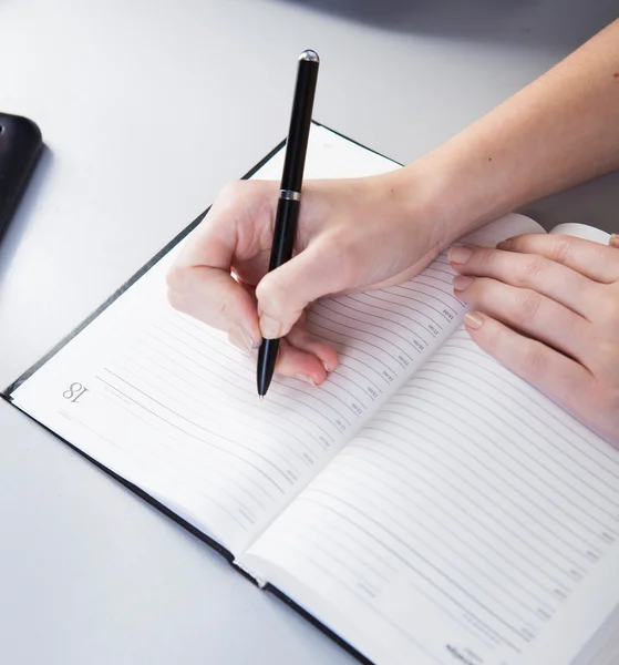 Business woman in the workplace does records in a diary — Stock Photo, Image