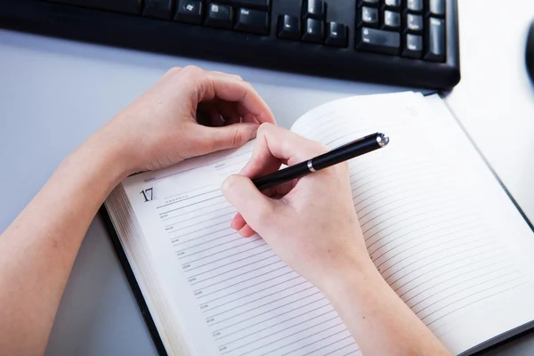 Business woman in the workplace does records in a diary — Stock Photo, Image