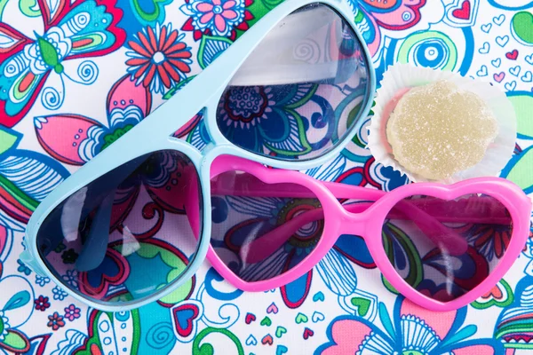 Gafas de sol en forma de corazón con caramelos de frutas sobre un fondo floral — Foto de Stock