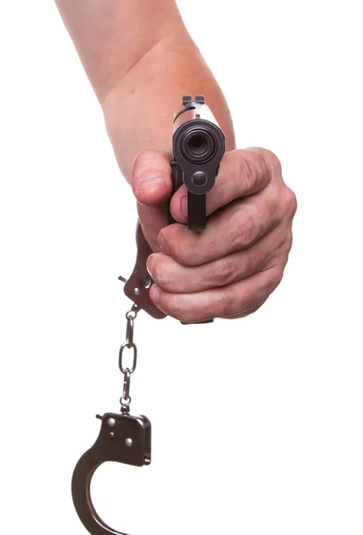 Male hand in police handcuffs and a gun isolated on a white background — Stock Photo, Image