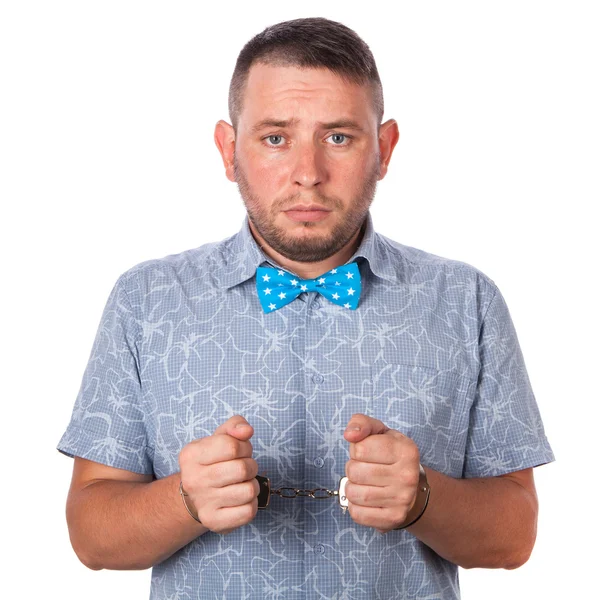 Adult male with beard in a blue bow tie in summer shirt in police handcuffs isolated on a white background — Stock Photo, Image