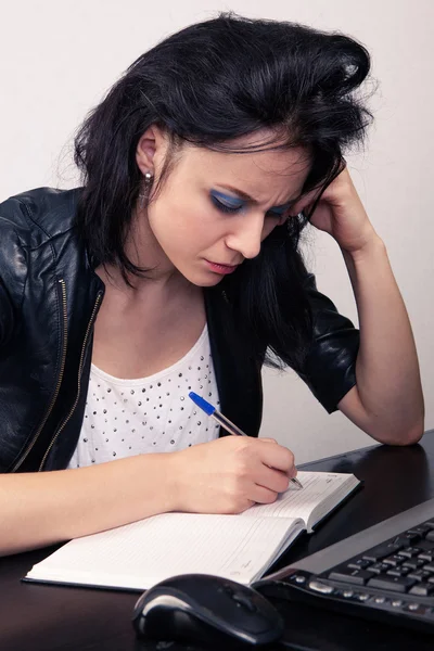 Ufficio ragazza che lavora su un computer e fa record in un diario su uno sfondo bianco — Foto Stock