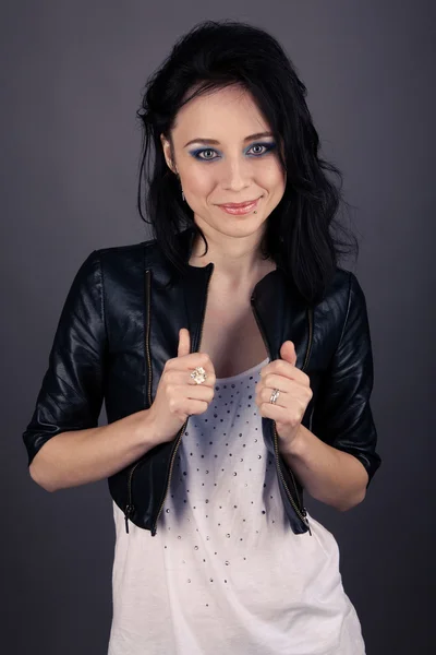 Pretty girl in leather jacket with piercings on a gray background — Stock Photo, Image