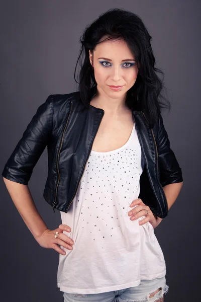 Pretty girl in leather jacket with piercings on a gray background — Stock Photo, Image