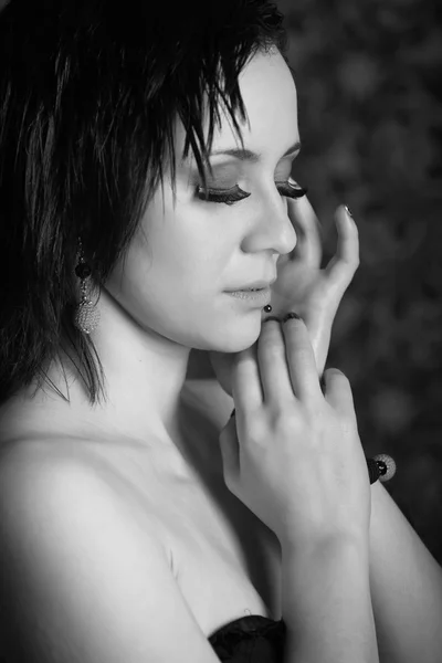 Black and white portrait of a beautiful brunette girl with earrings in a black dress — Stock Photo, Image