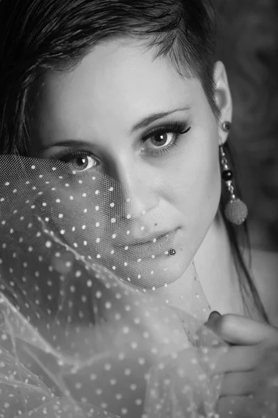 Zwart en wit portret van een mooie brunette meisje met oorbellen in een zwarte jurk — Stockfoto
