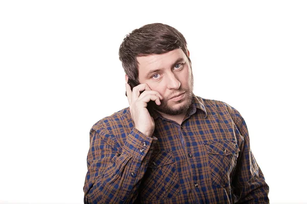 Serious man in a plaid shirt talking on the phone isolated on wh — Stock Photo, Image